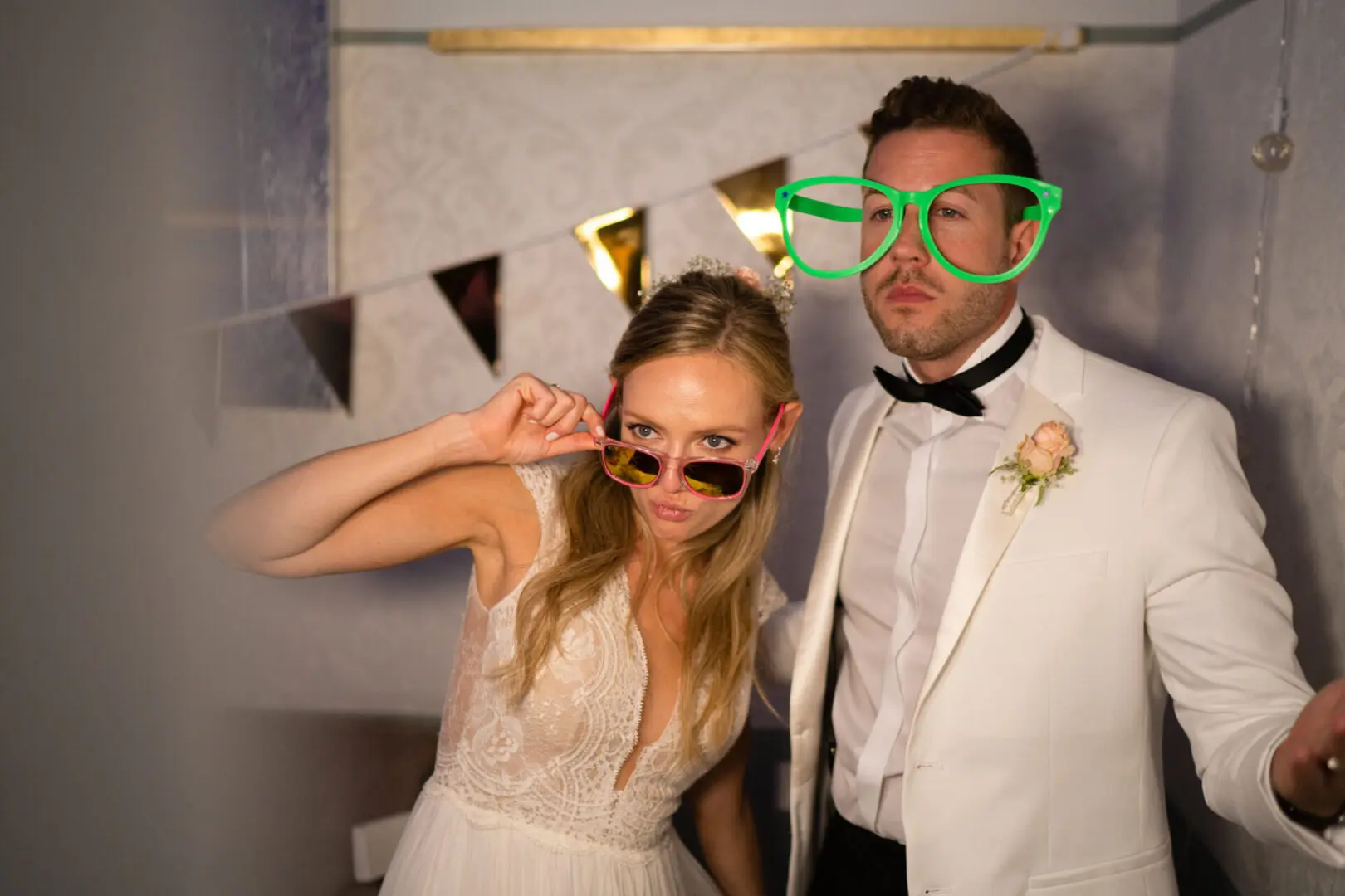 Bride and groom wearing oversized glasses, posing.